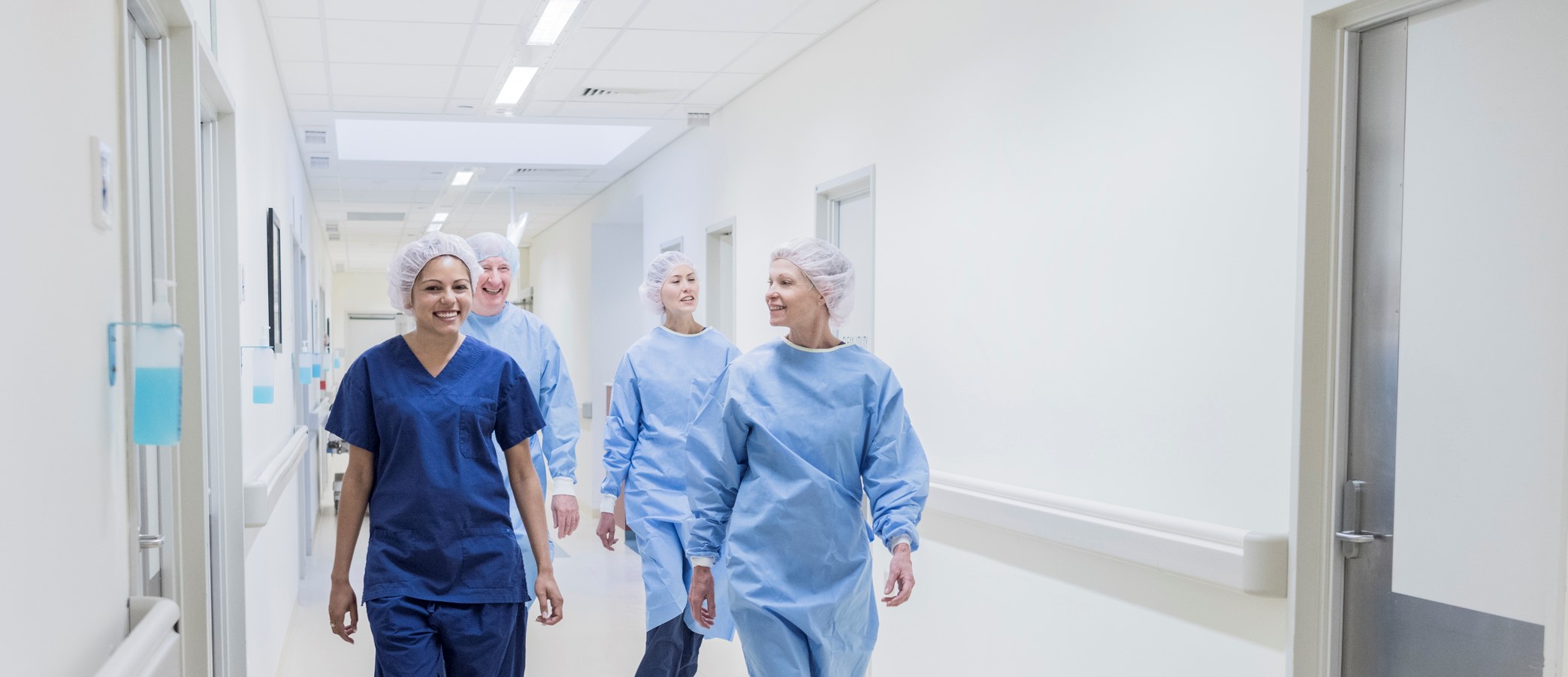 Surgical team walking down hospital corridor, front view